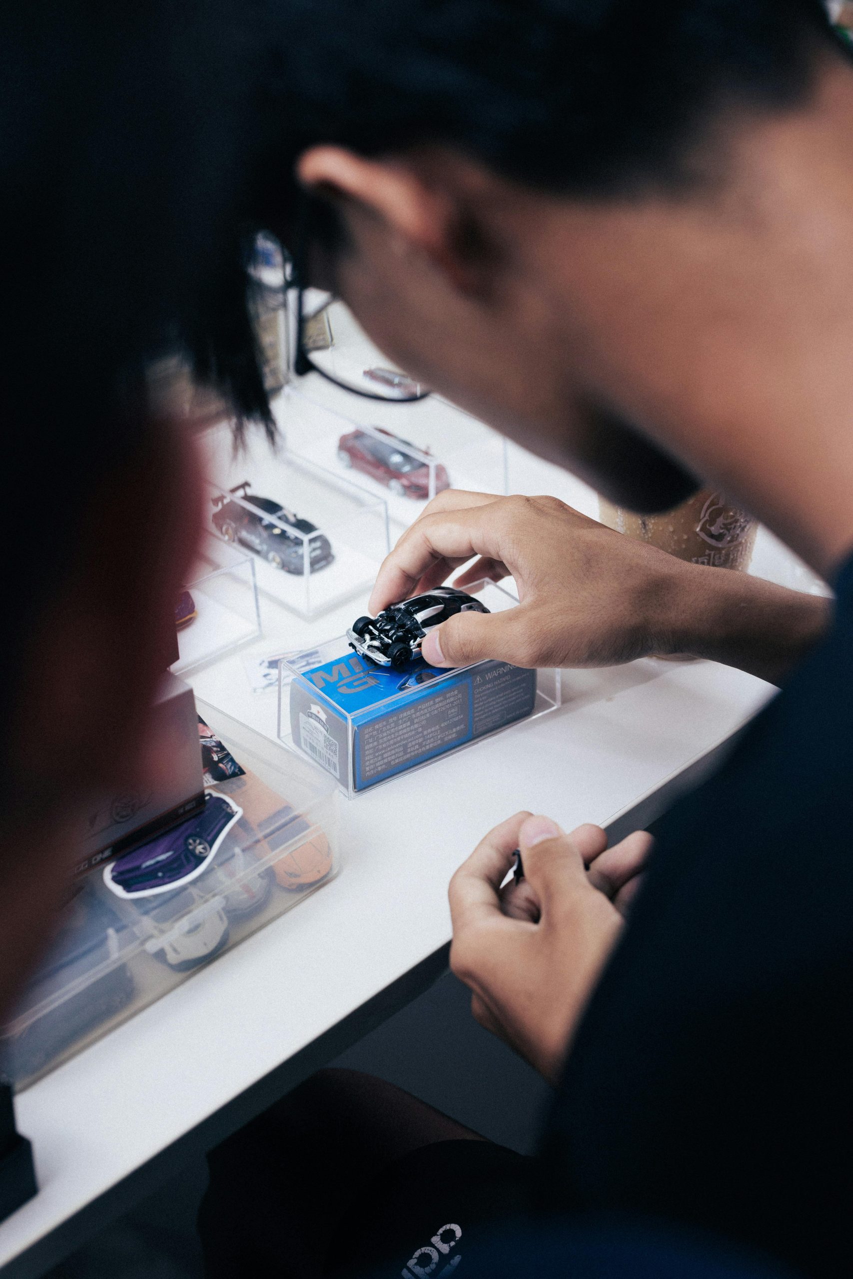 Hands interacting with scale model cars during a meet in Phnom Penh, Cambodia.